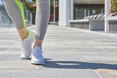 Kadınla beyaz spor ayakkabı şehirde açık çalıştırmak için hazır güneşli bir gün