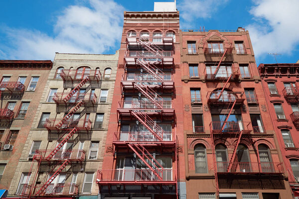 Typical building facades with fire escape stairs, sunny day in Soho, New York