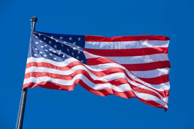 Amerikan veya ABD bayrağı bayrak direği, rüzgarla açık mavi gökyüzü