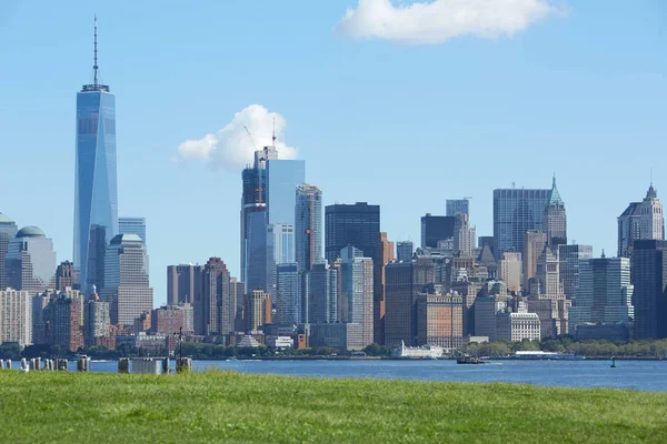 Skyline de Nueva York con torre Liberty y hierba verde en un día soleado . —  Fotos de Stock