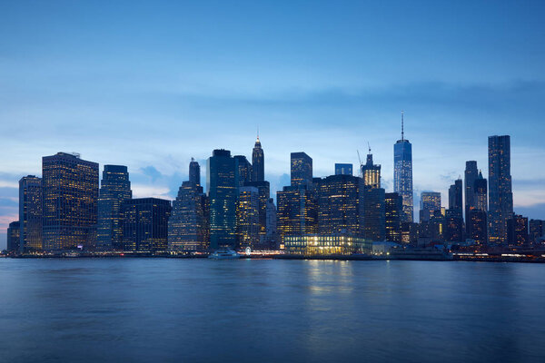 New York city skyline with illuminated buildings in the blue evening hour, Hudson river