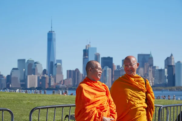 Dos monjes budistas con vestido naranja frente al horizonte de la ciudad de Nueva York en un día soleado —  Fotos de Stock