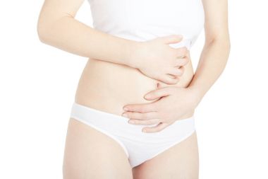 Karın ağrısından muzdarip genç bir kadın beyazlar içinde izole edilmiş.