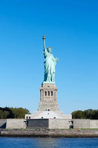 Статуя Свободы с пьедесталом и островом Свободы в солнечный день в Нью-Йорке — стоковое фото
