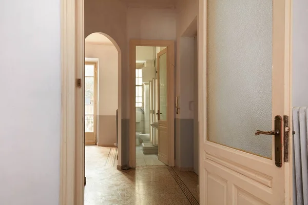 Old apartment interior view with open wooden door and tiled floor