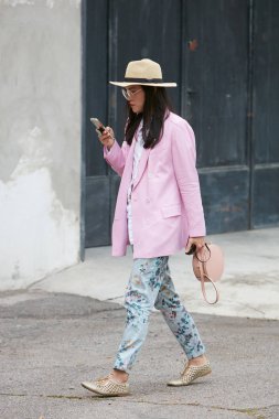 Arthur Arbesser moda defilesinden önce pembe ceketli ve çiçekli pantolonlu kadın, Milan Moda Haftası tarzı. 