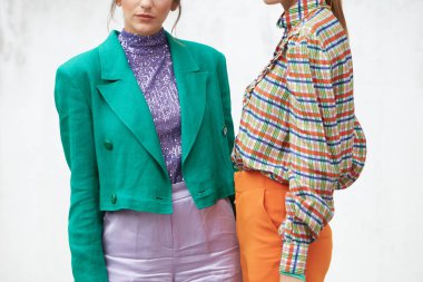 Arthur Arbesser defilesinden önce yeşil ceketli ve turuncu pantolonlu kadınlar, Milan Moda Haftası tarzı. 