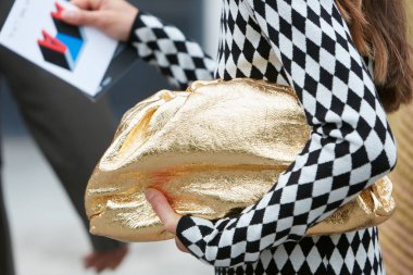 Altın çantalı ve siyah beyaz kazaklı kadın. Arthur Arbesser moda defilesinden önce, Milan Moda Haftası tarzı. 