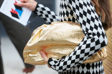 Woman with golden bag and black and white checkered sweater before Arthur Arbesser fashion show, Milan Fashion Week street style  clipart