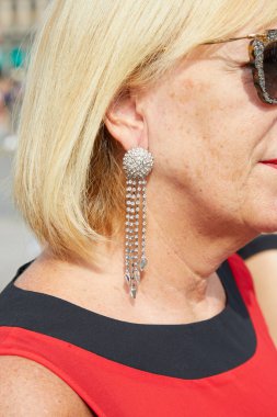 Tiziano Guardini defilesinden önce beyaz mücevherli küpe takan kadın, Milan Moda Haftası tarzı. 