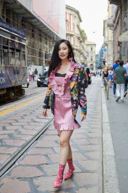 Calcaterra moda defilesinden önce pembe elbiseli ve çiçekli bir kadın, Milan Moda Haftası tarzı. 