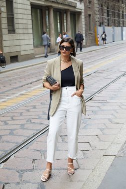 Calcaterra moda defilesinden önce beyaz pantolonlu ve bej ceketli kadın, Milan Moda Haftası tarzı. 