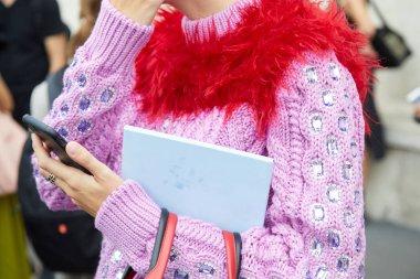 Prada defilesinden önce pembe kazaklı ve kırmızı kürklü bir kadın, Milan Moda Haftası tarzı. 