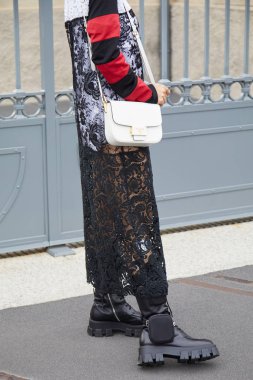 Beyaz Prada deri çantalı ve siyah dantelli bir kadın. Prada defilesinden önce, Milan Moda Haftası tarzı. 