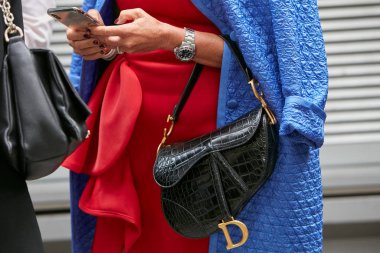 Dior siyah timsah çantalı kadın ve Rolex Submariner saati, Emporio Armani moda defilesinden önce akıllı telefona bakıyor, Milan Moda Haftası tarzı. 