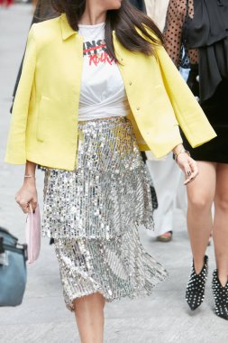 Sarı ceketli ve gümüş pullu bir kadın Emporio Armani moda defilesinden önce yürüyor, Milan Moda Haftası tarzı. 
