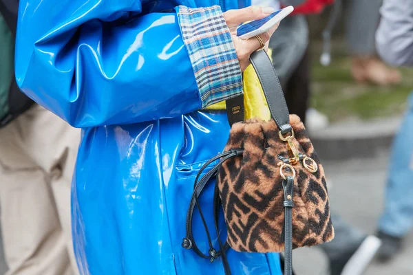 Mavi plastik ceketli, kahverengi kürklü Fendi çantalı kadın Emporio Armani moda defilesinden önce akıllı telefona bakıyordu. Milan Moda Haftası tarzı. — Stok fotoğraf