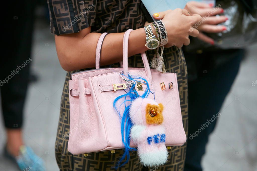 MILAN, ITALY - SEPTEMBER 19, 2019: Woman with pink coat and bag with golden chains before Fendi fashion show, Milan Fashion Week street style