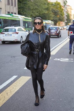 Bottega Veneta moda defilesinden önce yürüyen siyah deri ceketli ve güneş gözlüklü kadın, Milan Moda Haftası tarzı. 