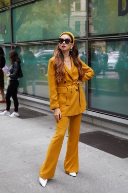 Emporio Armani moda defilesinden önce sarı ceketli ve pantolonlu kadın, Milan Moda Haftası tarzı. 