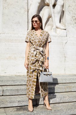 Genny moda defilesinden önce sürüngen derisinden elbisesi ve gri çantası olan kadın, Milan Moda Haftası tarzı. 