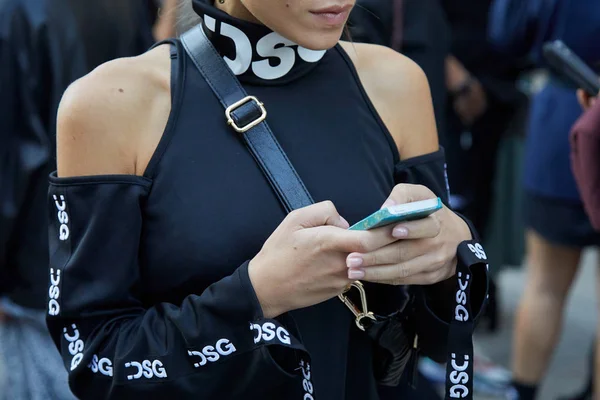 Vrouw met Disgiusto zwart streetwear shirt op zoek naar smartphone voor Bottega Veneta modeshow, Milaan Fashion Week street style — Stockfoto