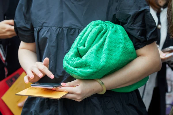 Mujer con bolsa de cuero verde y vestido negro mirando el teléfono inteligente antes del desfile de moda Fendi, Milan Fashion Week street style —  Fotos de Stock