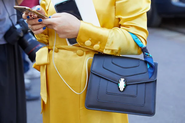 Mujer con vestido amarillo y bolso Bulgari Serpenti mirando el smartphone antes del desfile de moda Luisa Beccaria, Milan Fashion Week street style — Foto de Stock