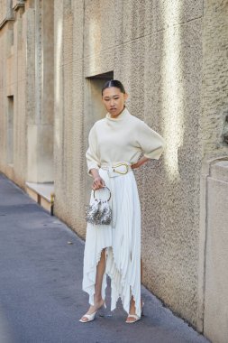Salvatore Ferragamo defilesinden önce uzun pileli etek ve süveter giyen kadın, Milan Moda Haftası tarzı. 