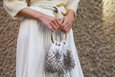 Beyaz pileli etekli ve çantalı kadın Salvatore Ferragamo defilesinden önce altın yüzük, Milan Moda Haftası tarzı. 