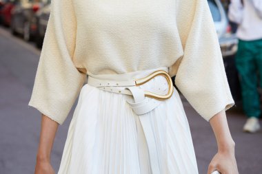 Beyaz etekli, beyaz deri kemerli, Salvatore Ferragamo defilesinden önce altın tokalı kadın, Milan Moda Haftası tarzı. 