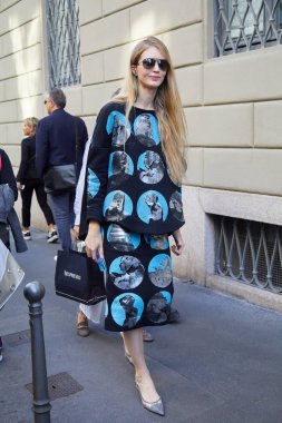 Giorgio Armani moda defilesinden önce siyah elbiseli, yuvarlak mavi tasarımlı bir kadın, Milan Moda Haftası tarzı. 