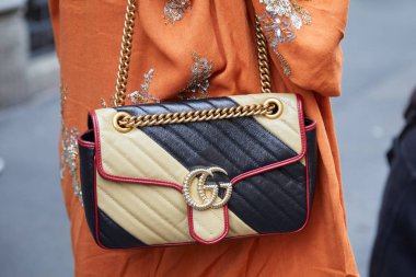 Sarı ve siyah Gucci çantalı kadın altın zincirli ve turuncu elbiseli Giorgio Armani defilesinden önce, Milan Moda Haftası tarzı 