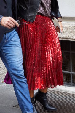 Woman with red glitter pleated skirt walking before Giorgio Armani fashion show, Milan Fashion Week street style  clipart