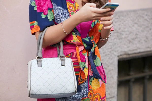 Frau mit floralem Kleid und grauer Tasche beim Blick aufs Smartphone vor der Modenschau von Giorgio Armani, Mailänder Modewoche Streetstyle — Stockfoto