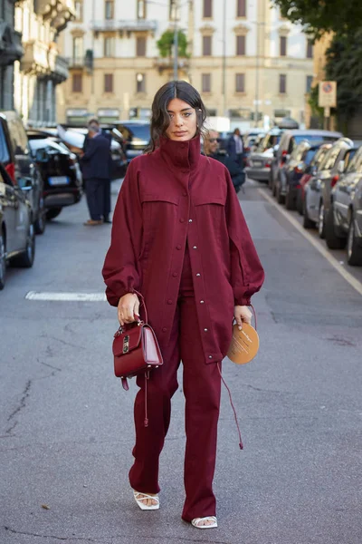 Donna con giacca e pantaloni rosso scuro e borsa in pelle prima della sfilata Salvatore Ferragamo, Milano Fashion Week street style — Foto Stock