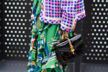 Gucci moda defilesinden önce altın kemerli ve yeşil etekli siyah deri çantalı kadın, Milan Moda Haftası tarzı. 