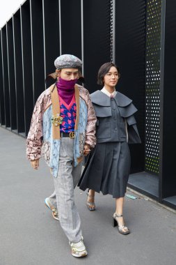 Gucci moda defilesinden önce gri elbiseli ve renkli sürüngen deri ceketli kadın ve adam, Milan Moda Haftası 