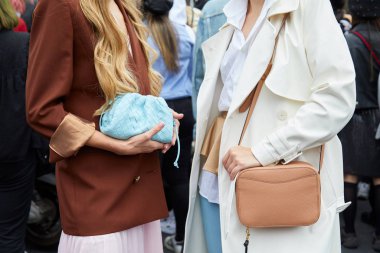 Gucci moda defilesinden önce turkuaz, kahverengi deri çanta ve beyaz trençkot giyen kadın, Milan Moda Haftası tarzı. 