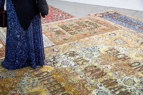 Mulher olhando para tapetes com escritos durante a abertura da feira de arte contemporânea Artissima no palácio Oval Lingotto em Turim, Itália — Fotografia de Stock