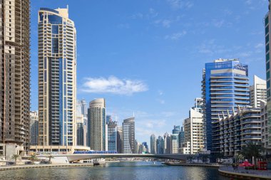 Dubai Marina gökdelenleri ve kanalı güneşli bir günde köprü, Dubai 'de açık mavi gökyüzü