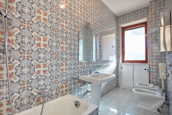 Інтер'єр ванної кімнати з квітковою плиткою, сонячне світло — стокове фото