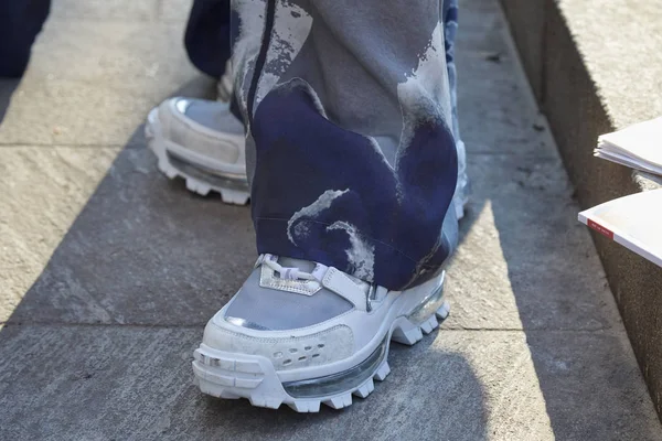 Мужчина в белых кроссовках и синих и серых брюках перед показом Emporio Armani, уличный стиль Миланской недели моды — стоковое фото