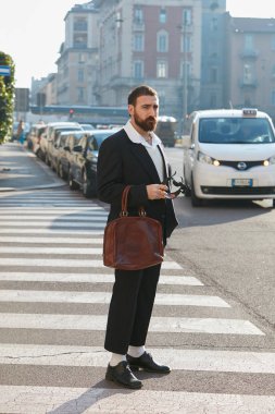 Salvatore Ferragamo defilesinden önce siyah ceketli, pantolonlu ve beyaz gömlekli adam, Milan Moda Haftası tarzı. 