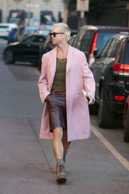 Salvatore Ferragamo defilesinden önce pembe ceketli ve kahverengi deri pantolonlu bir adam, Milan Moda Haftası tarzı. 
