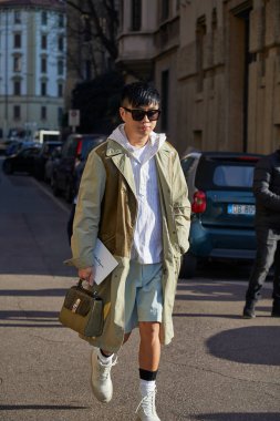 Salvatore Ferragamo moda defilesinden önce beyaz çizmeli ve bej ceketli bir adam, Milan Moda Haftası tarzı. 