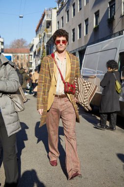 Etro defilesinden önce bej renkli ceketli ve Etro çantalı bir adam, Milan Moda Haftası tarzı. 