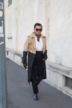 Prada defilesinden önce bej ve siyah trençkotlu adam, Milan Moda Haftası tarzı. 