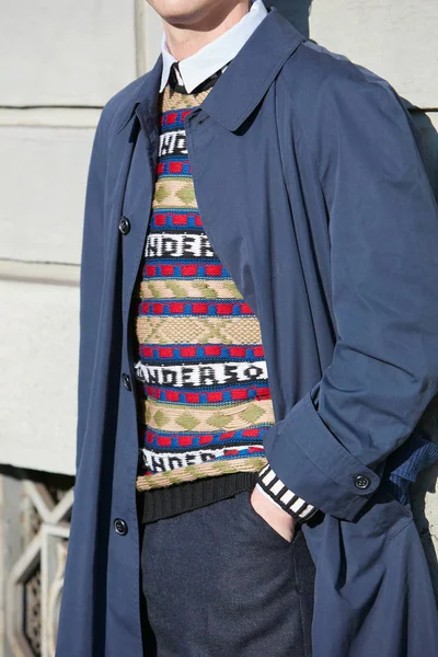 Мужчина в синем пальто и свитере в красном, синем, зеленом и бежевом цветах перед показом мод Сальваторе Феррагамо, в стиле Недели моды в Милане — стоковое фото