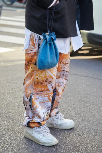 Homme avec des baskets Nike blanches et un pantalon au design orange avant le défilé Salvatore Ferragamo, Milan Fashion Week street style — Photo